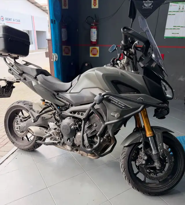 Yamaha Tracer 900 GT cinza estacionada na oficina