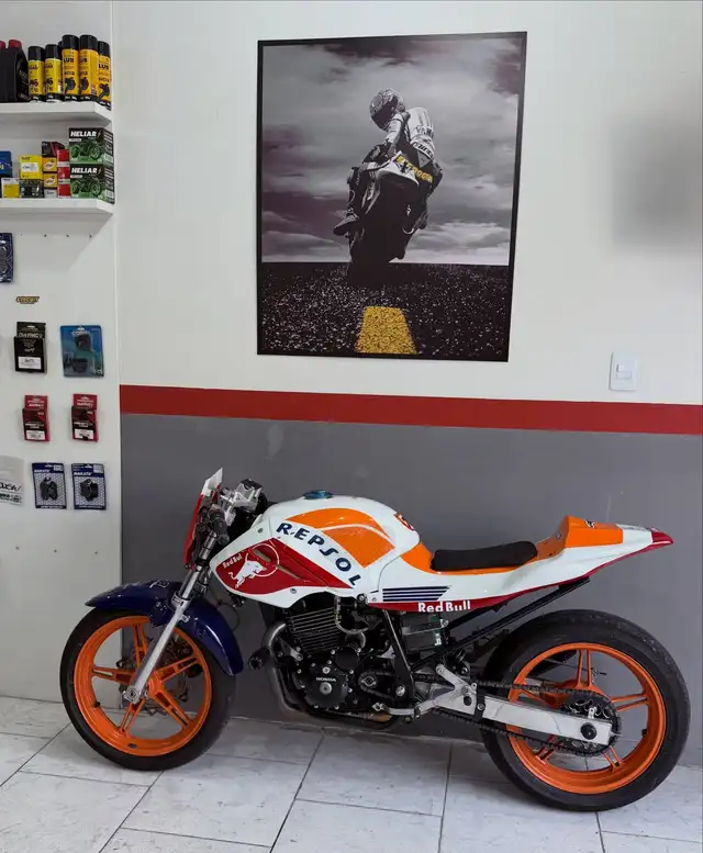 Twister 450 com pintura Repsol na oficina nova, parede branca com faixa vermelha